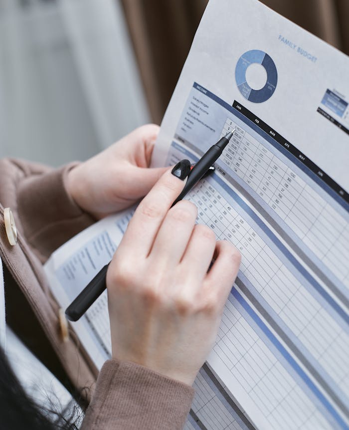 Hands holding a pen review a family budget document with graphs and tables.